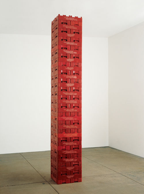 A tall column of red soda cases stacked vertically