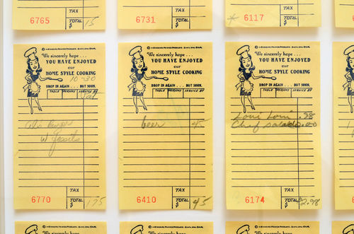 Close up view of yellow receipts from Al's Cafe, hung in a grid