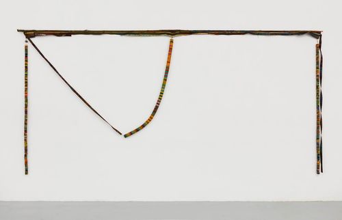 A colorful, yarn wrapped piece hanging on a wall