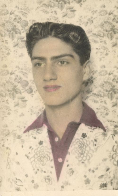 Photograph of a young Van Leo wearing a floral jacket that matches the backdrop