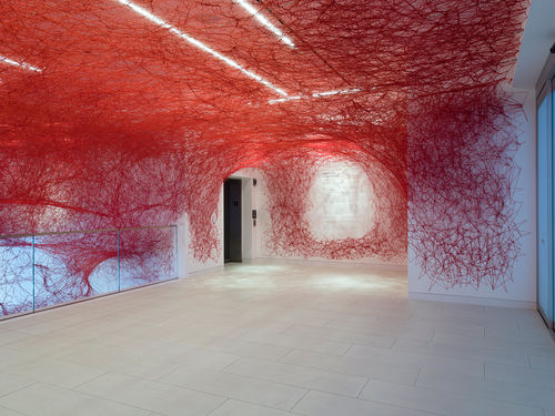 Installation view of Chiharu Shiota's installation enveloping the museum lobby in a web of red string