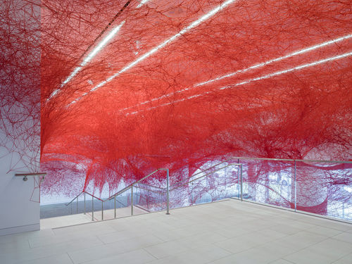 Installation view of Chiharu Shiota's installation enveloping the museum lobby in a web of red string
