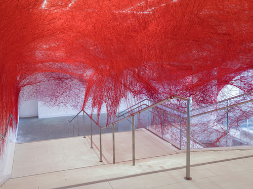 Installation view of Chiharu Shiota's installation enveloping the museum lobby in a web of red string