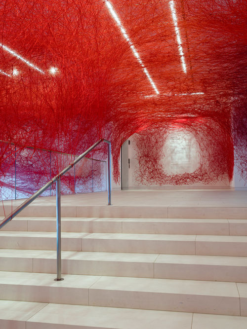 Installation view of Chiharu Shiota's installation enveloping the museum lobby in a web of red string