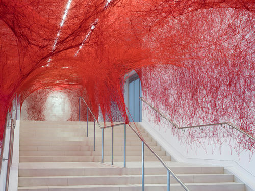 Installation view of Chiharu Shiota's installation enveloping the museum lobby in a web of red string