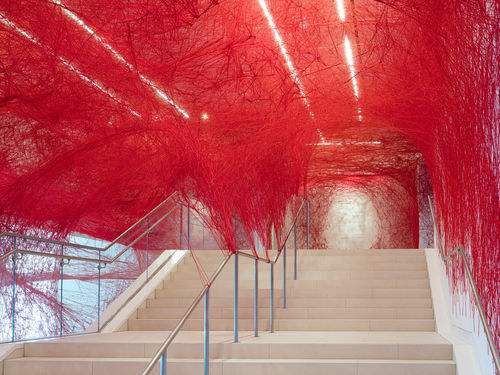 Installation view of Chiharu Shiota's installation enveloping the museum lobby in a web of red string