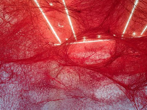 Installation view of Chiharu Shiota's installation enveloping the museum lobby in a web of red string