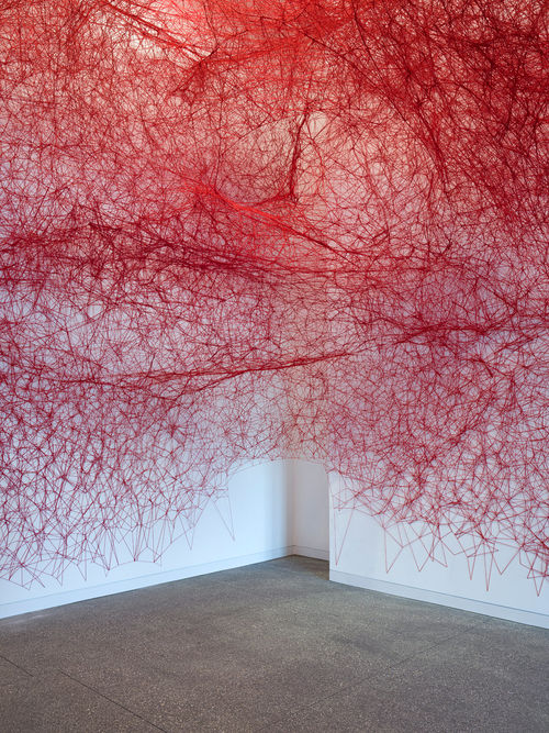 Installation view of Chiharu Shiota's installation enveloping the museum lobby in a web of red string
