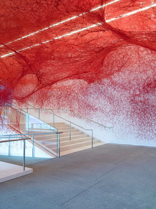 Installation view of Chiharu Shiota's installation enveloping the museum lobby in a web of red string