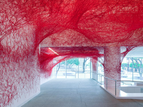 Installation view of Chiharu Shiota's installation enveloping the museum lobby in a web of red string