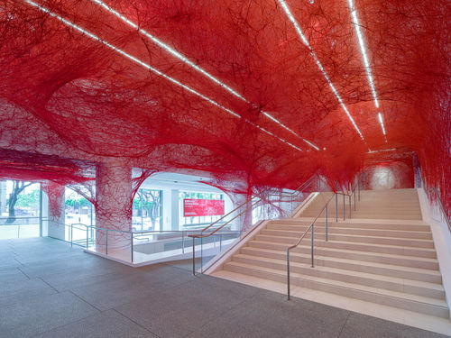 Installation view of Chiharu Shiota's installation enveloping the museum lobby in a web of red string