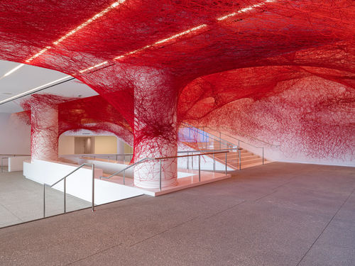 Installation view of Chiharu Shiota's installation enveloping the museum lobby in a web of red string