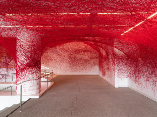 Installation view of Chiharu Shiota's installation enveloping the museum lobby in a web of red string