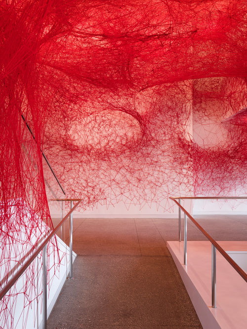 Installation view of Chiharu Shiota's installation enveloping the museum lobby in a web of red string
