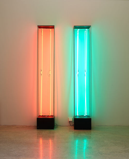 Two vertical steel cases with neon lights inside in orange and green