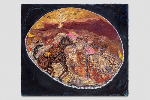 A man rides a horse in front of a dessert landscape