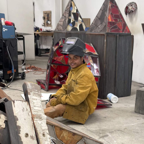Chiffon Thomas sitting in a studio, wearing a welding helmet