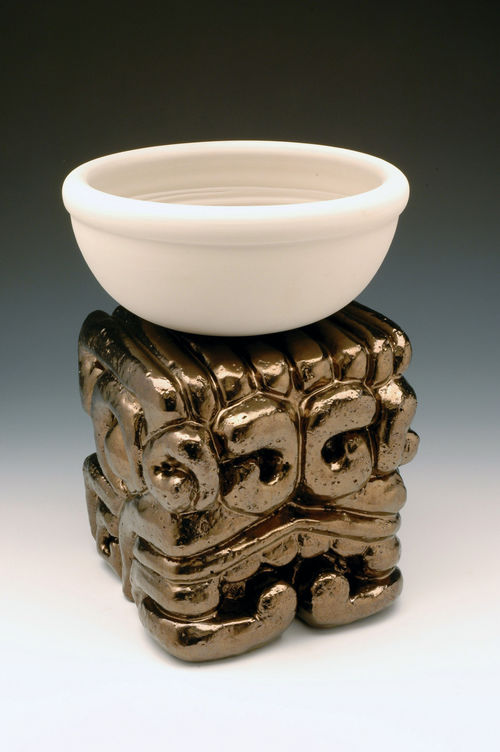 A plain bowl sits on an ornate metallic stand