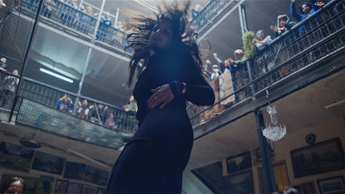 A woman dances in a building courtyard