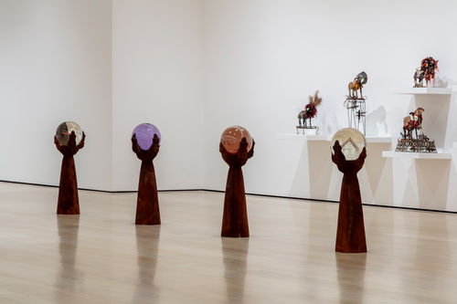 Series of four sculptures in the shape of a claw gripping a colorful orb