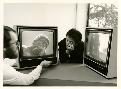 Nam June Paik rests between two TV monitors