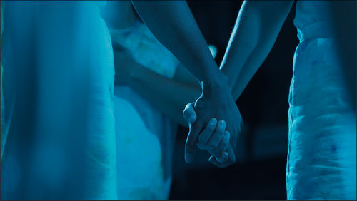 Close up of three performers holding hands