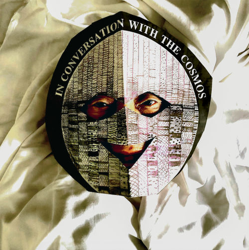 Photo of David Medalla wearing a mask that reads "in conversation with the cosmos"