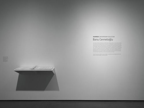 Installation view depicting a binder of video metadata displayed on wall-mounted shelf, the exhibition title and intro text installed to the right