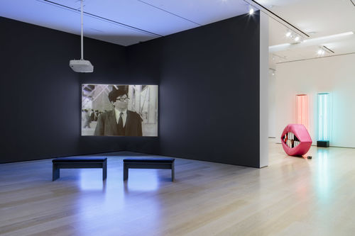Installation image showing single-channel video artwork and multimedia sculptures, including a mouth with pink lips and mirrors for teeth