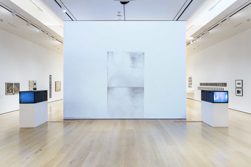 Installation image showing a black-and-white wall-mounted artwork, with vintage TV monitors installed on either side