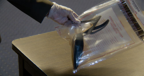 A gloved hand holds an evidence bag holding a pair of pruning shears