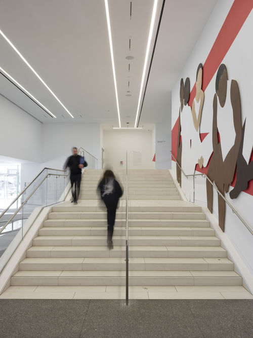 Hammer lobby wall installation depicting a group of abstracted figures, young gymnasts in leotards and high buns, which red architectural lines painted on white
