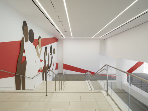 Hammer lobby wall installation depicting a group of abstracted figures, young gymnasts in leotards and high buns, which red architectural lines painted on white