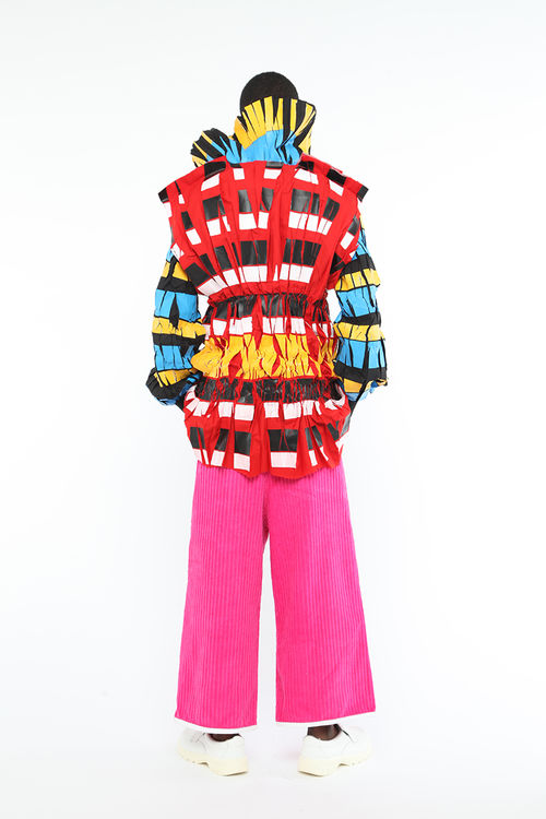 Model, seen from behind, wearing bright pink pants and a multi-colored jacket