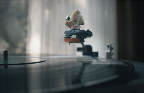 An anthropomorphized shell stands on a record player stylus