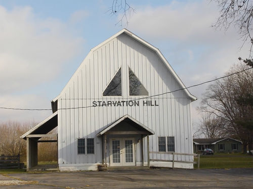 A wood building with the sign Starvation Hall