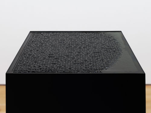 Black plinth with an undulating surface