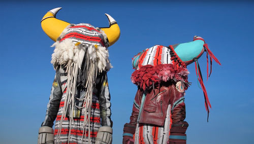 Two figures in colorful, horned costumes