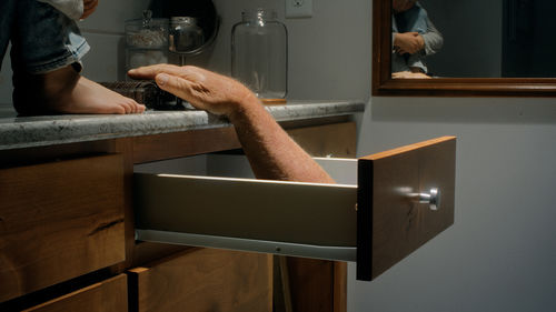 A hand reaches from a kitchen drawer toward a box of oreos