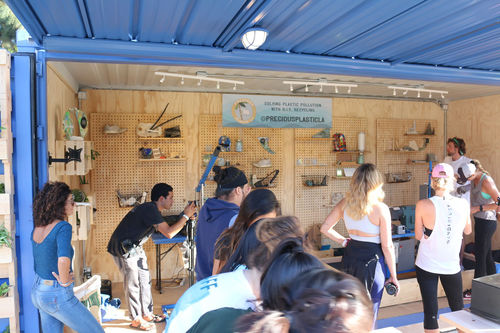 A group of people in a storage container outfitted to showcase recycled plastic goods