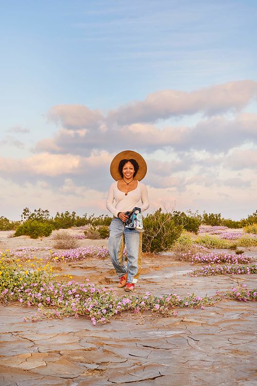 Krystle Hickman, wearing a sunhat and holding a camera in a desert landscape