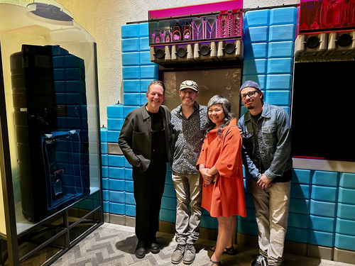 Four people stand in front of an art installation