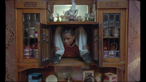 A figure crammed into a cabinet filled with trinkets