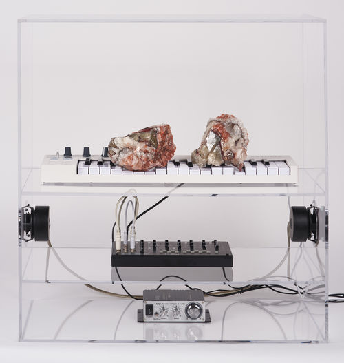 Art installation featuring a white keyboard with two large calcite crystals on top