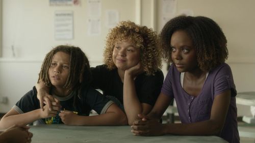 three young girls sit side by side at class