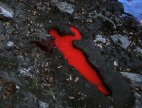 A silhouette dug into the dirt, filled with bright red liquid