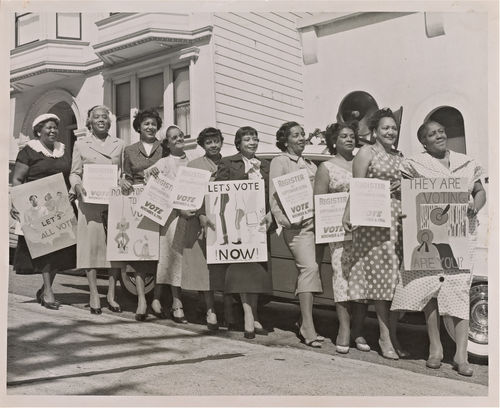A black-and-white photograph of ten women lined up with signs along the Citizenship Education Project's motorcade route encouraging voting and voter registration.