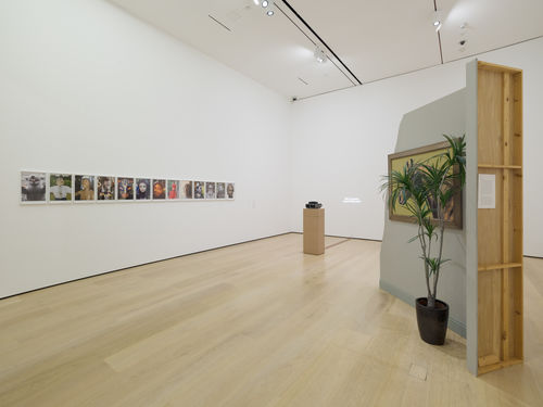 installation image with framed works, sculpture, and projected work