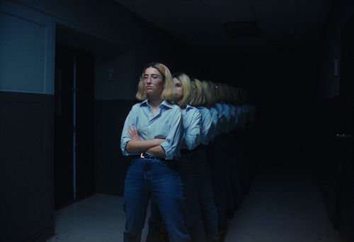 A woman standing with her arms crossed, reflected ad infinitum