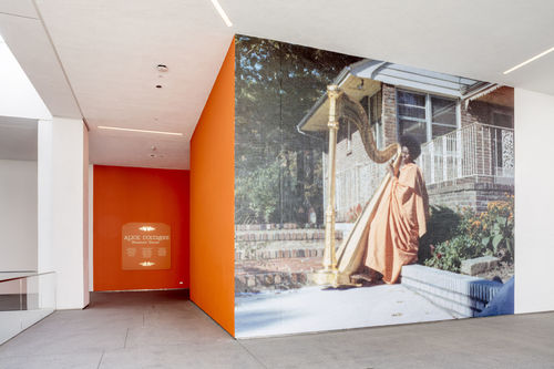 Large-scale image of Alice Coltrane playing a harp, printed on an exterior museum wall